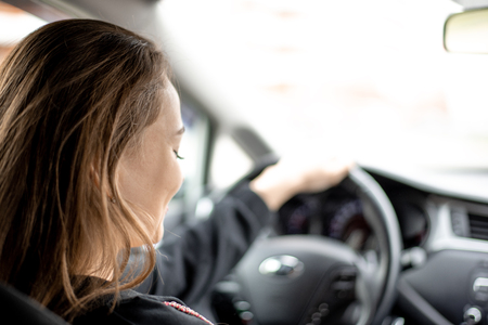 Girl driving a car . Removed from the back seat. The machine panel is blurred.の写真素材