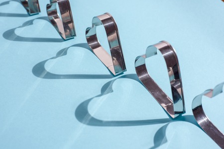 Shadows of metal shapes in the form of a heart on blue backgroundの写真素材