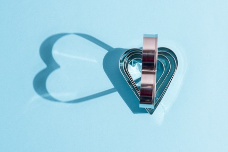Shadows of metal shapes in the form of a heart on blue background