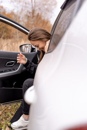 Beautiful young woman sitting in the car in the driver's seat with the door openの写真素材