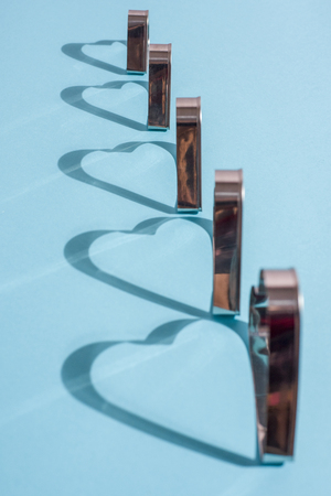 Shadows of metal shapes in the form of a heart on blue backgroundの写真素材