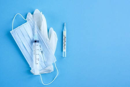 Medical disposable syringe, ampoule, gloves, mask and thermometer on blue background . The view from the top.の写真素材