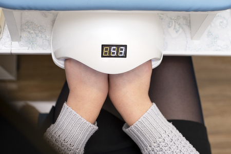 In the nail salon woman dries nail Polish in a nail lamp for dryingの写真素材