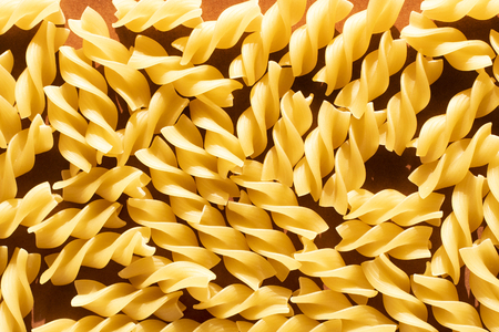 Macaroni in the form of yellow spirals on brown background. Top viewの写真素材