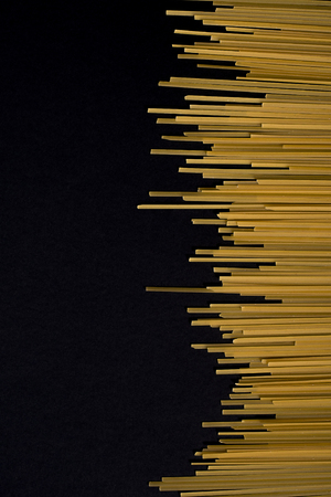 Raw yellow flat spaghetti on black backgroundの写真素材