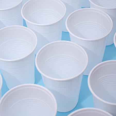 Disposable plastic white empty cups on blue background