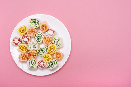 Turkish sweets of different colors on a white plate on pink backgroundの写真素材