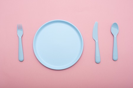 Blue plastic tableware : plate, fork, knife and spoon on pink background. Flat layの写真素材