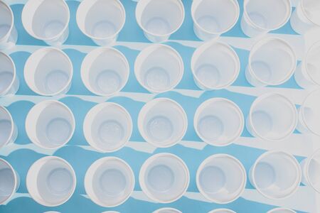 Disposable plastic white empty cups on blue background