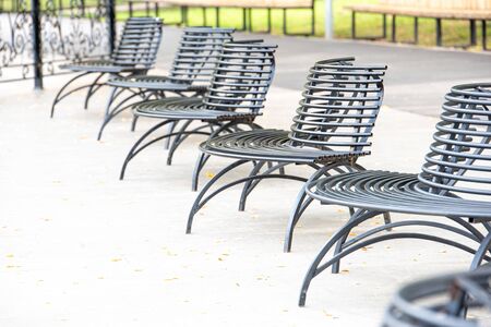 Iron black bench in park in autumn dayの写真素材