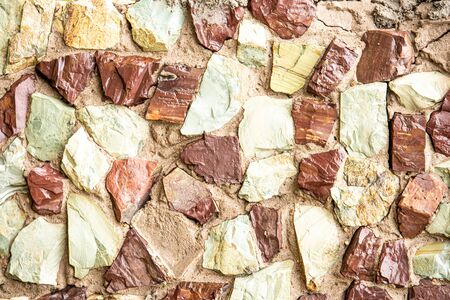 Stone wall of natural stones of red green yellow colors . Background.の写真素材