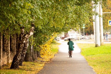 City park with walking people in autumn dayの写真素材