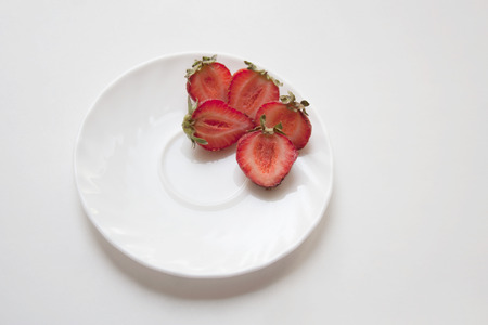 Sliced strawberries on small ceramic plate  isolated on white backgroundの写真素材