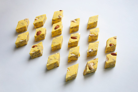 Yellow halva slices with melon taste stuffed with almond and cashew nuts isolated on white backgroundの写真素材