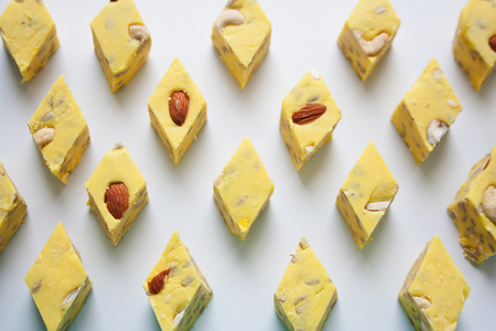 Yellow halva slices with almond and cashew nuts abstract rhombus pattern on white backgroundの写真素材