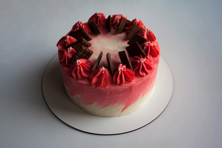 Cherry mousse cake decorated with whipped cream and milk chocolate bars isolated on white backgroundの写真素材