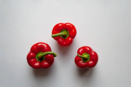 Three red bell peppers isolated on white background from a high angle viewの写真素材