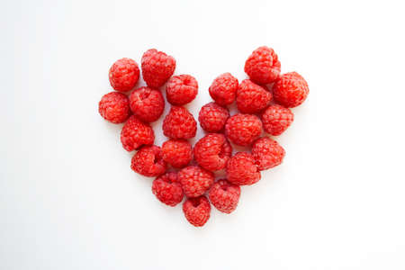 Juicy raspberries heart shaped composition isolated on white background