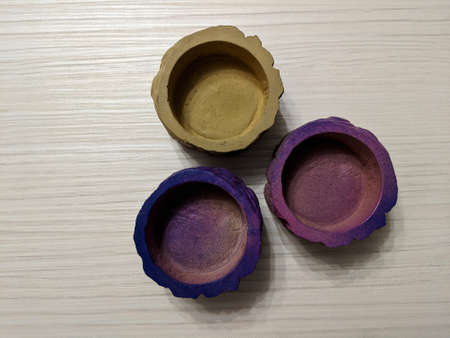 Three colored concrete pots isolated on light wooden background from a high angle viewの写真素材