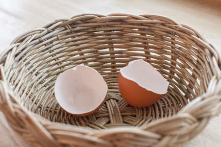 Egg shells in a wicker basket on a wooden floor