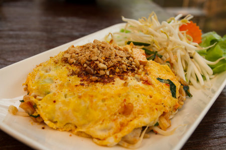 crushed peanuts.Ground peanuts sprinkled on Thai food on a white plate and a wooden tableの写真素材