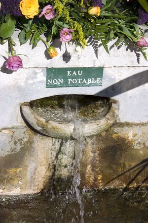 Public fountain in a french village adorned with rosesの写真素材