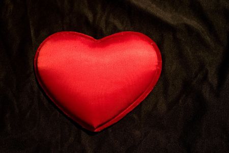 Puffed pillow satin heart on black background suitable for Valentines or any message needing a heart. Plenty of room for text. Focus is on the center of the heart.の写真素材