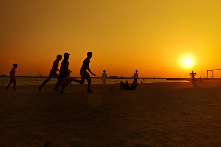 Amateur playing football  at beach  during sunset.の写真素材