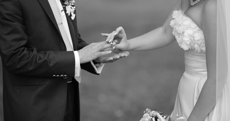 Bride puts a ring on finger of her groom. Picture in black and white. Togetherness.の写真素材
