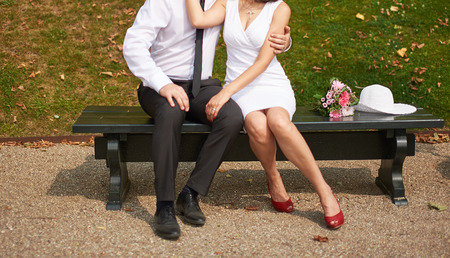 Newlyweds sitting on bench in park.の写真素材