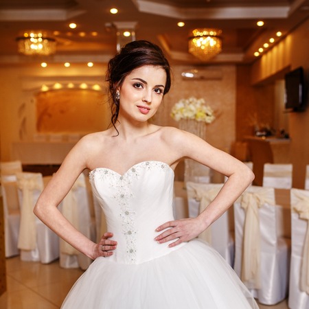 Young brunette bride wearing gorgeous wedding dress posing in restaurant.の写真素材