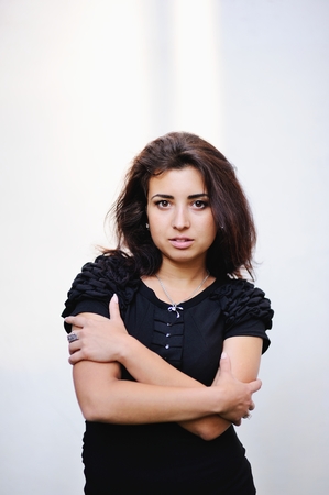 Fashion potrait of beautiful woman in black dress against white wallの写真素材