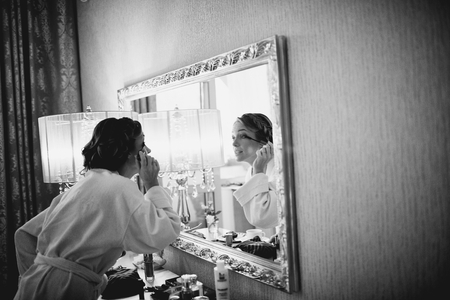 Bridal morning in black and white. Young beautiful bride applying wedding make-up.の写真素材