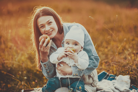 Happy young mother and lovely daughter holding apple at countryside.の写真素材