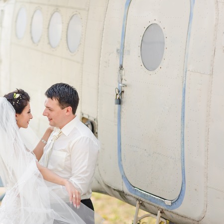 Bride and groom next to old aircraft. Wedding summer couple together posing against brick wall.の写真素材
