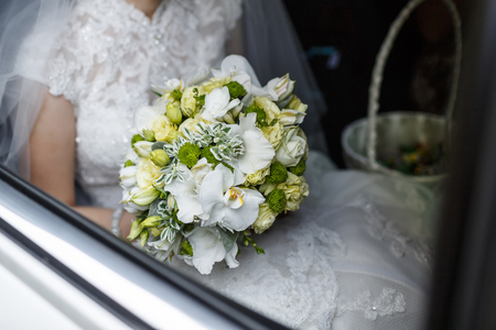 Bride with wedding bouquet sitting in a car.の写真素材