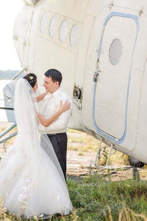 Bride and groom next to old aircraft. Wedding summer couple together posing against brick wall.の写真素材