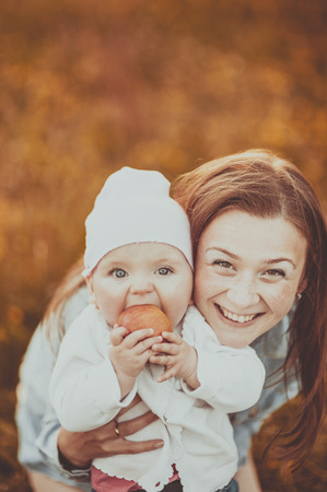 Happy young mother and lovely daughter holding apple at countryside.の写真素材