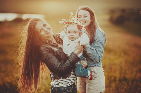 Happy family of mom sister and lovely daughter in sunset light.の写真素材