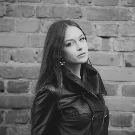 Young female with beautiful long hair, wearing leather jacket, posing outside.の写真素材