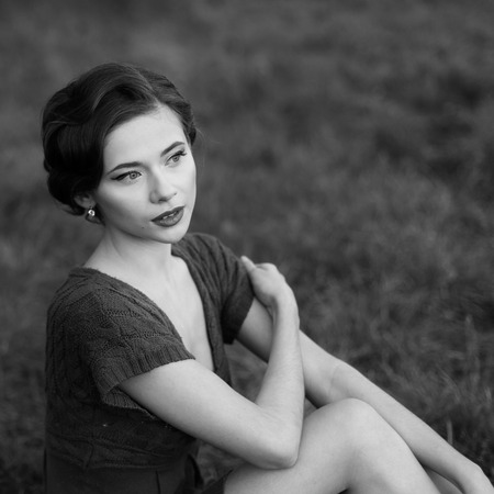 Young woman with retro coiffure posing outside. Portrait in black and white.の写真素材