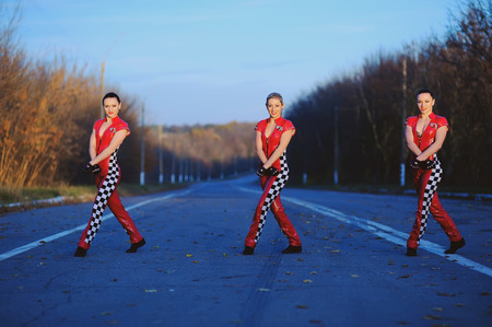 Three girls wearing overalls  of mechanics on a roadの写真素材