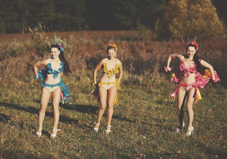 Three funny attractive females wearing dresses, dancing in fieldの写真素材