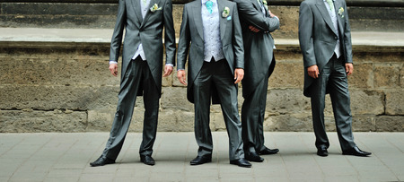 Stulish groom in tuxedo and his friends posing at street.の写真素材