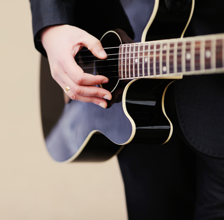 man in suit  playing an acoustic guitar outsideの写真素材