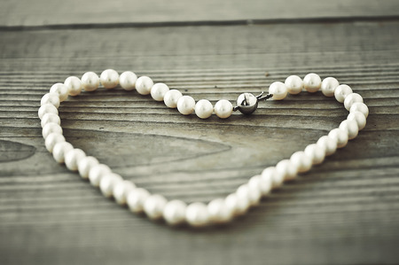 Beads with shape of heart on wooden background.の写真素材