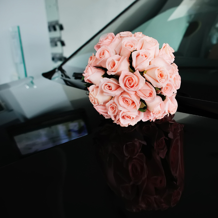 Beautiful Bridal bouquet of pink roses  on a black car.の写真素材
