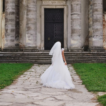 beautiful bride walking next to old churchの写真素材