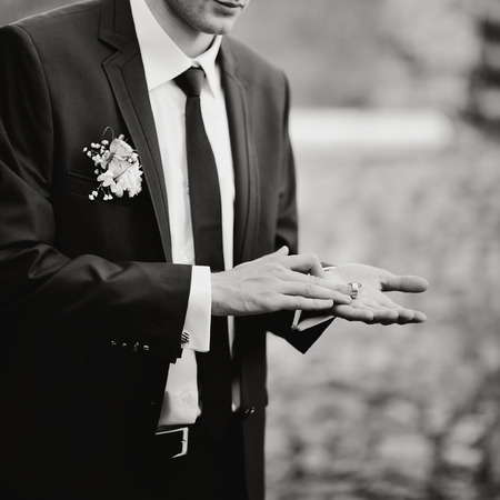 Groom shows two wedding rings on his palmの写真素材