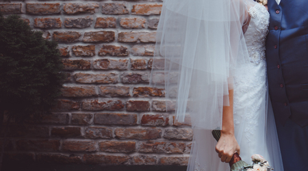 Young wedding couple next to brick wallの写真素材
